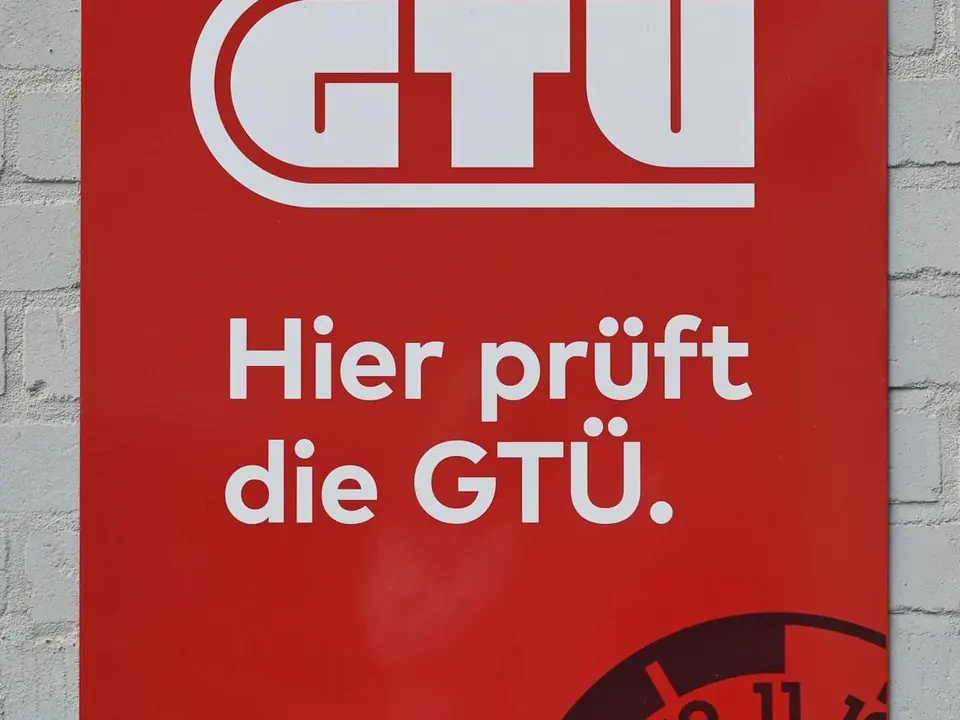 Roter GTÜ-Banner „Hier prüft die GTÜ“ am Werkstattgebäude.