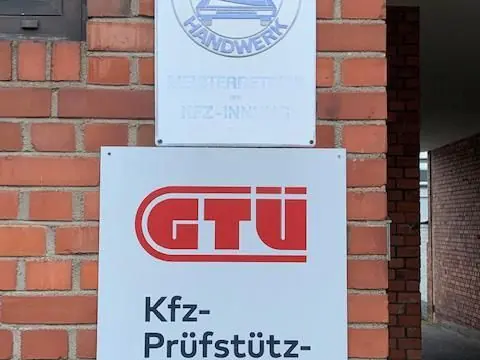 Schild „Kfz-Prüfstützpunkt“ und GTÜ-Logo an der Backsteinwand der Werkstatt.