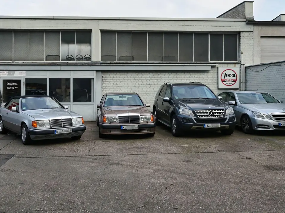Mehrere Kundenfahrzeuge parken vor dem Werkstattgebäude.