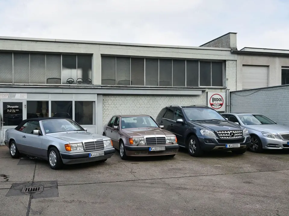 Mehrere Mercedes-Benz Fahrzeuge parken vor dem Werkstattgebäude.