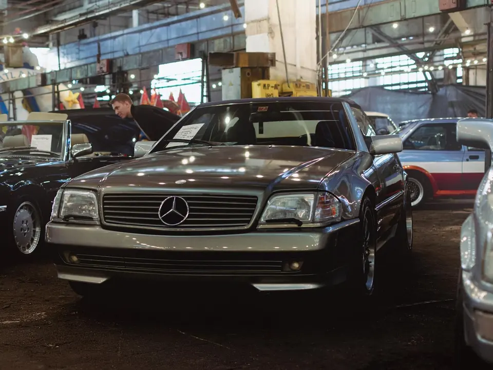 Ein Mercedes-Benz 300 SL steht neben weiteren Fahrzeugen.