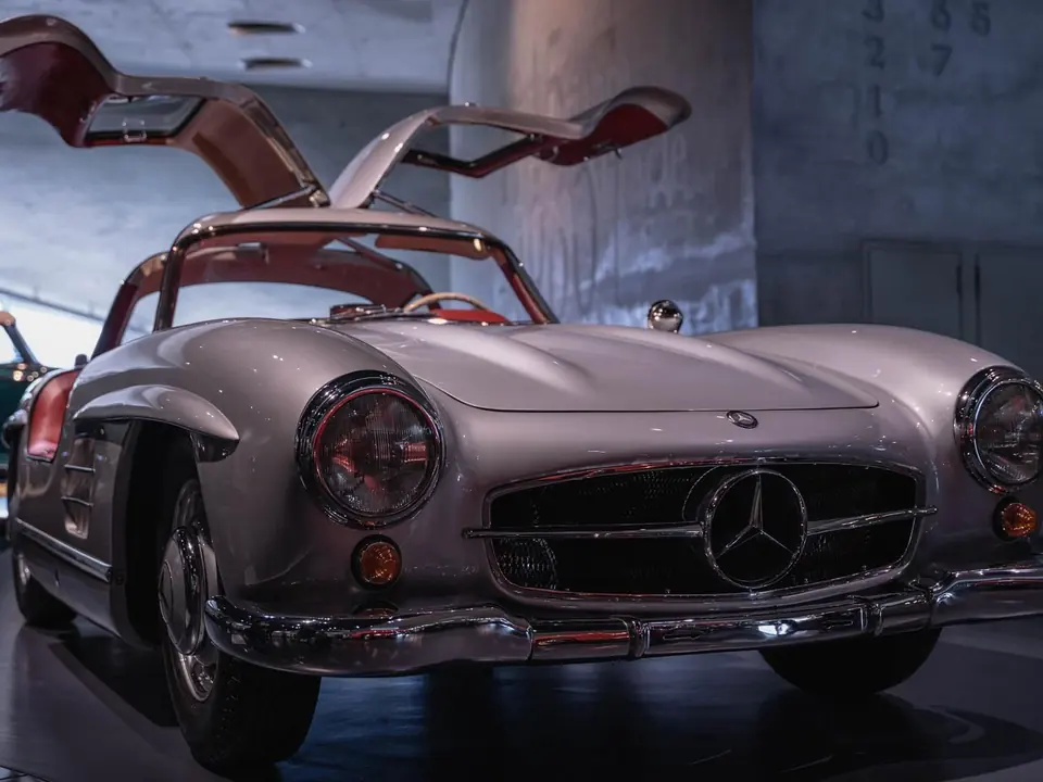 Ein silberner Mercedes-Benz mit geöffneten Türen in einer Garage.