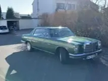 Ein grüner Mercedes-Benz Oldtimer parkt vor einem Wohnhaus.