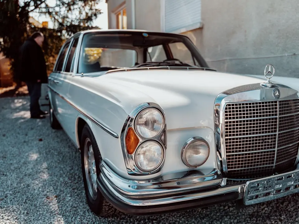 Ein weißer Mercedes-Benz Oldtimer in einer Hofeinfahrt.