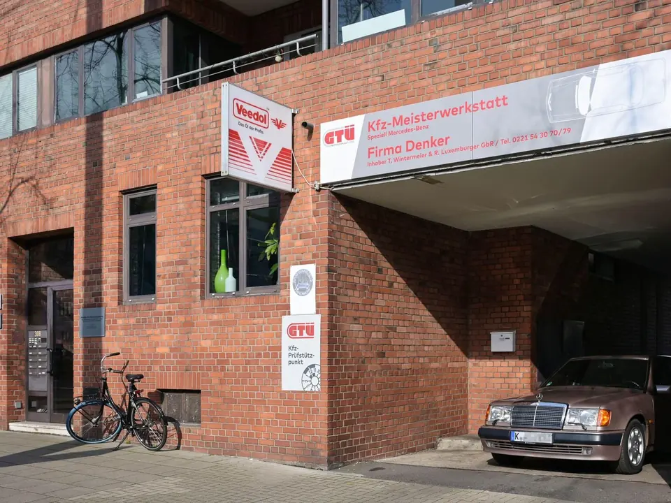 Ein Fahrzeug parkt vor dem Backsteingebäude der Werkstatt.