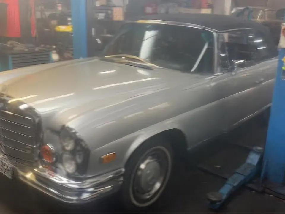 Ein silberner Mercedes-Benz Oldtimer steht auf der Hebebühne in der Werkstatt.