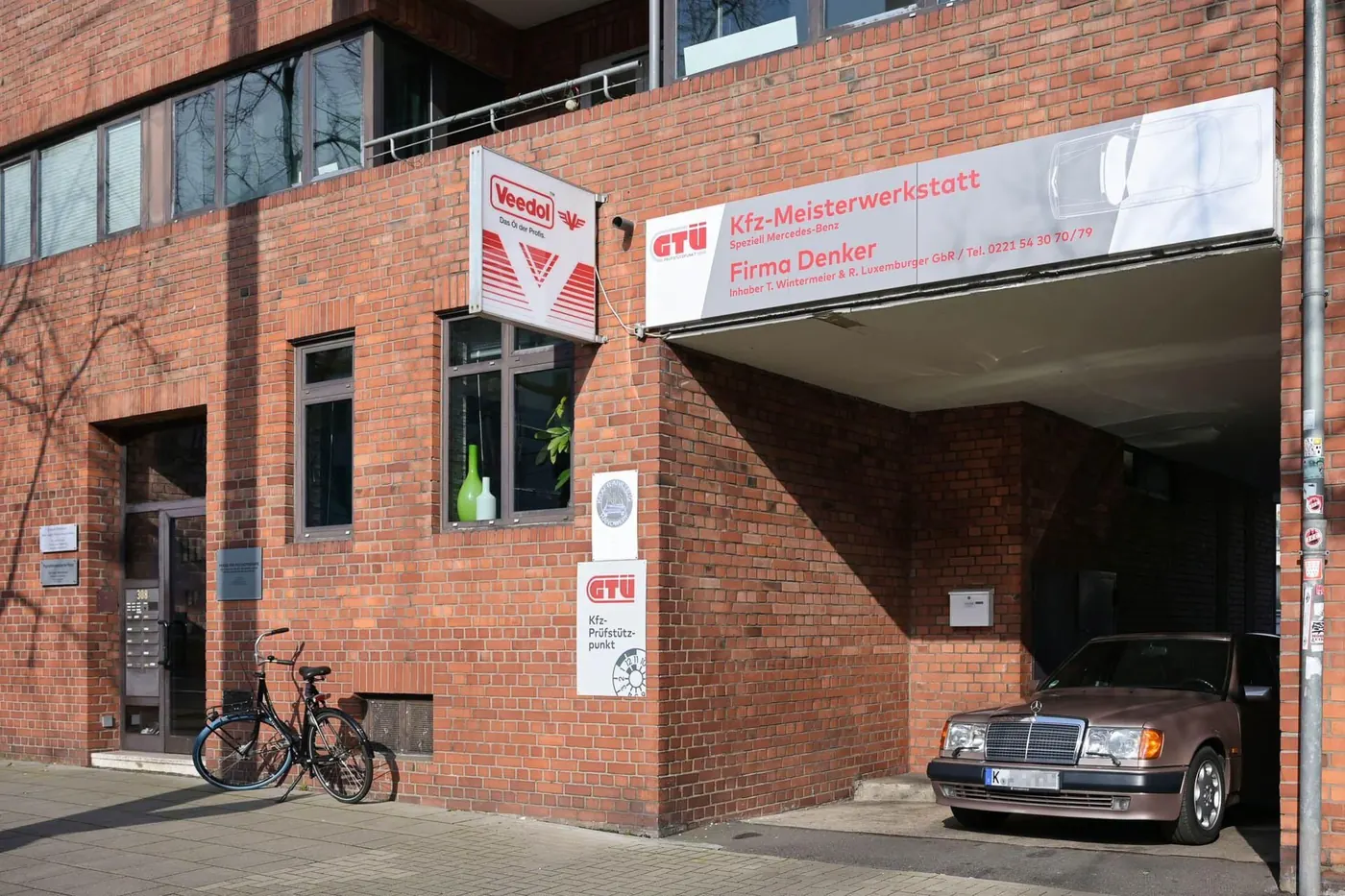 Ein Fahrzeug parkt vor dem Backsteingebäude der Werkstatt in der Aachener Straße.